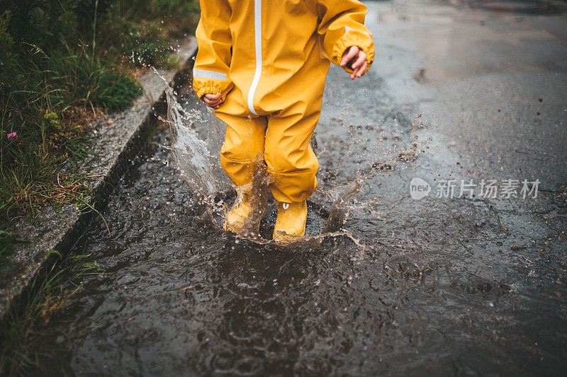 小男孩在雨中玩耍，跳进水里画画