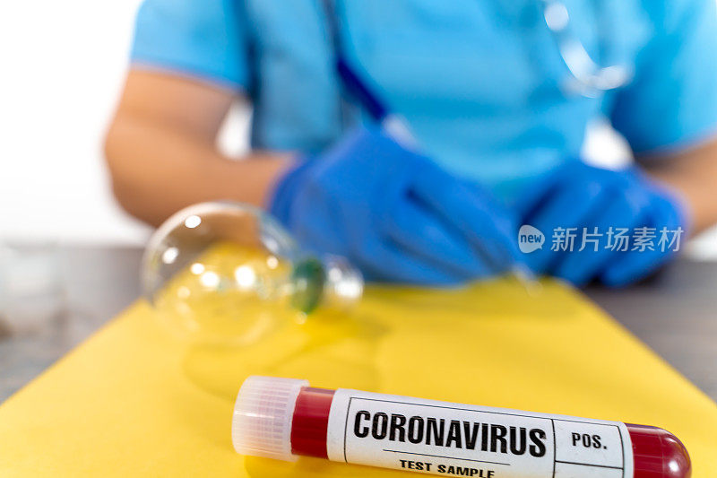 医生在黄色纸上写着COVID-19血液样本试管，特写