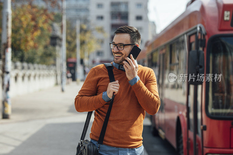 微笑的男人等公共汽车和打电话