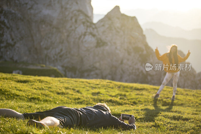 男友躺着用手机拍女友在山里的照片