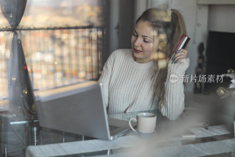 一个年轻漂亮的女人用信用卡在网上购物。一个拿着信用卡用笔记本电脑的少女。网上购物的概念