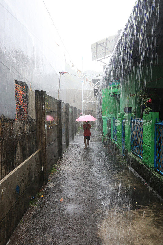 一个小女孩在倾盆大雨中带着雨伞。