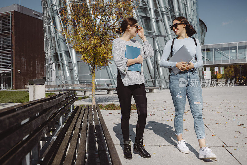 两个年轻女子，大学生，一起在外面散步