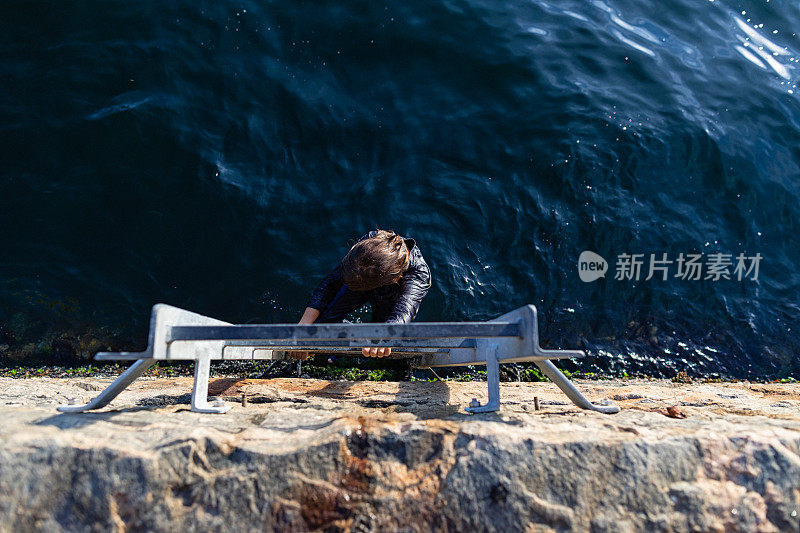 夏天，一个孩子在海边洗完澡后，站在梯子上离开了水