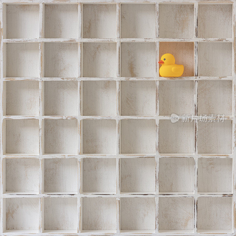 一只黄色的橡皮鸭孤零零地孤独地望着光亮，被困在一个空荡荡的木方鸽子洞里。