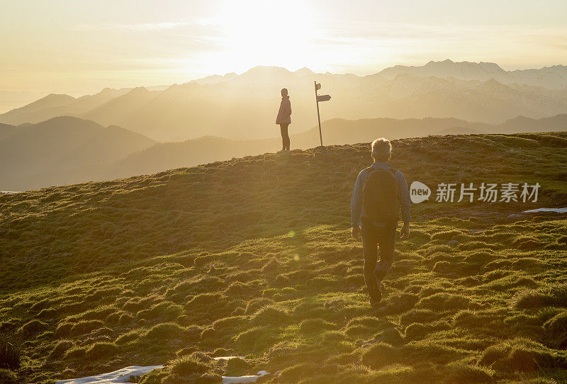 夫妇走在高高的草地上，路标