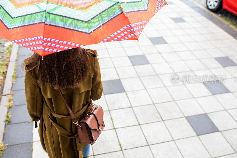 年轻女子撑着伞站在城市的瓷砖地板上