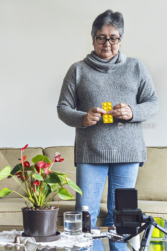 拉丁老年妇女在视频通话中照顾她的医生与她的药在桌子上的要求