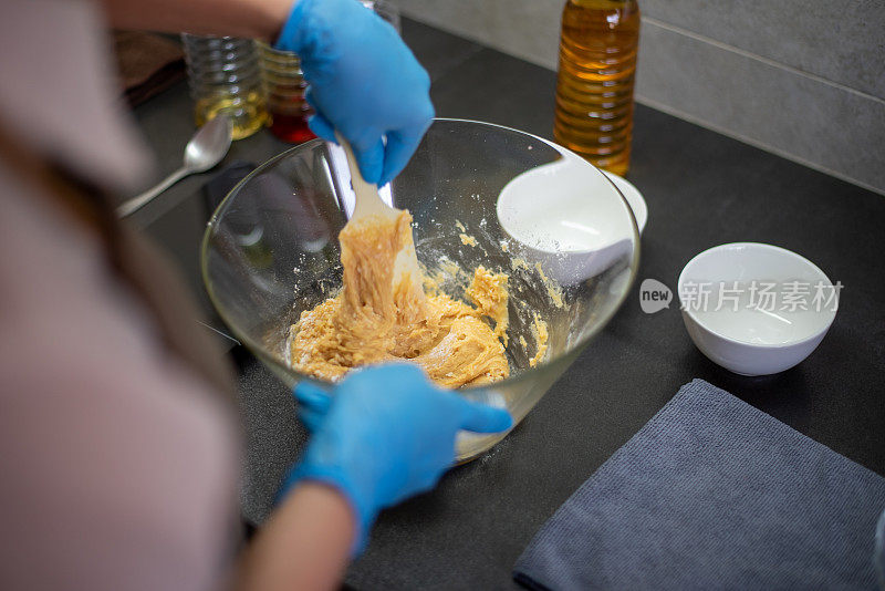 一位亚洲华人妇女在家里揉着食谱中的配料