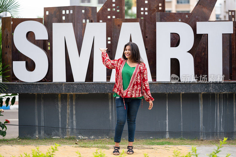 年轻女孩站在写着SMART的大字前面。