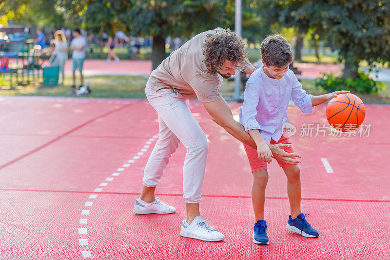 一个快乐的父亲和儿子正在享受户外和打篮球。