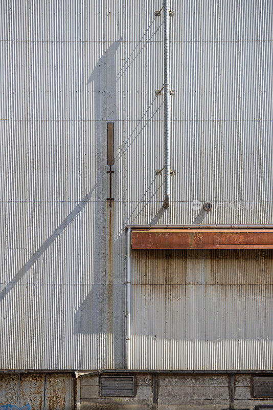 一旧工业建筑的墙，上面覆盖着波纹铁皮