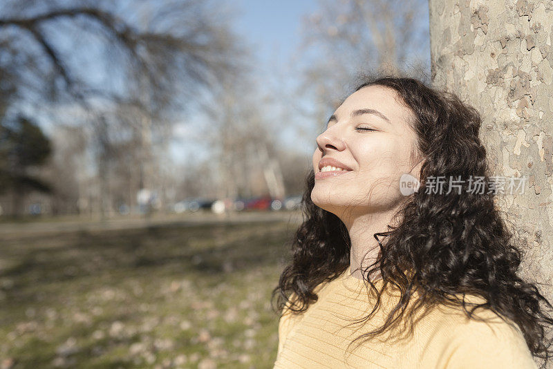 一个年轻女子的肖像享受太阳温暖她的脸