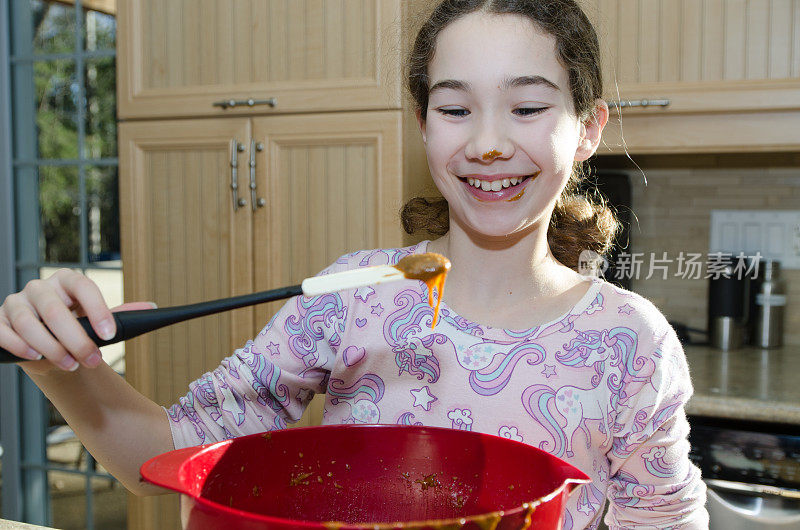 十几岁的女孩正津津有味地品尝着饼干混合物