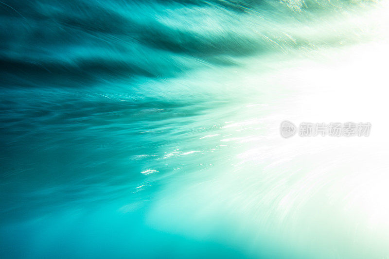 一种抽象的艺术场景，一个波浪在戏剧性的金色光线下在水下破碎