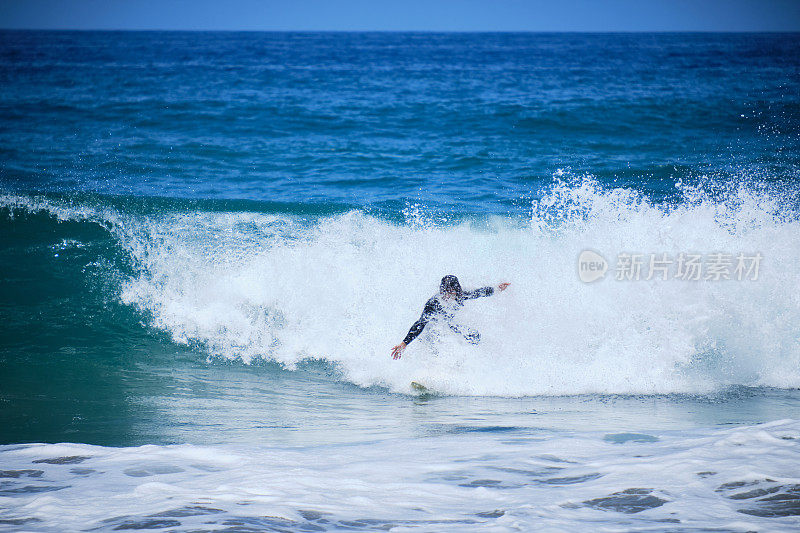 低角度，太阳能接头:在富埃特文图拉附近，一个很酷的年轻冲浪者雕刻了一波美丽的蓝色管子。运动男游客享受他的夏天航行在风景如画的加那利群岛。