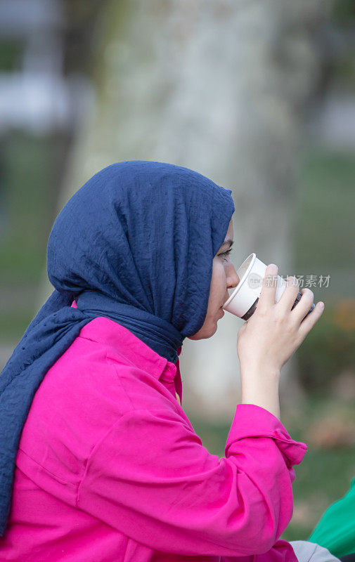 年轻女子正在公园里喝咖啡。