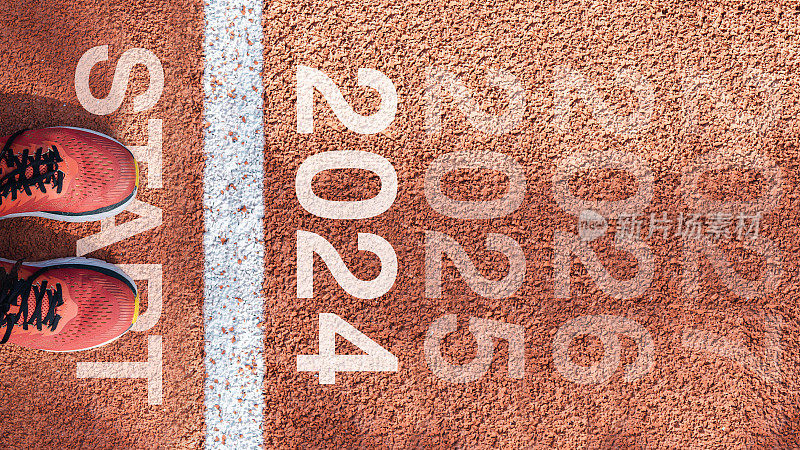 新的一年2024概念，成功的开始。文字2024写在柏油路上，男跑步者准备迎接新的一年。对挑战或职业道路和改变的概念。