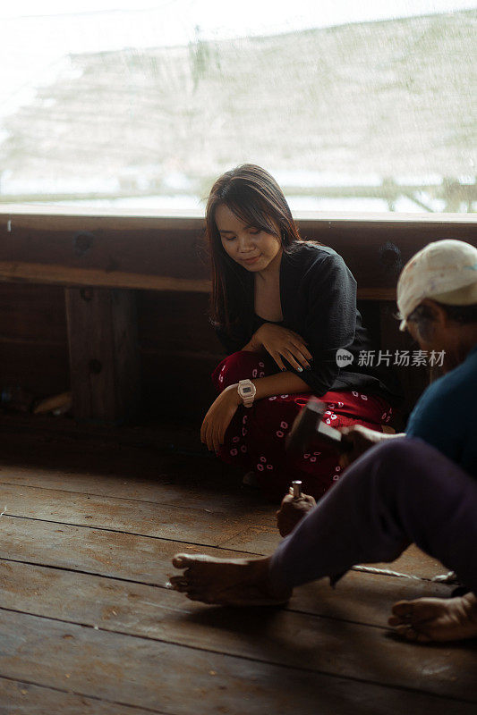 美丽的亚洲女性游客向当地工匠学习造船