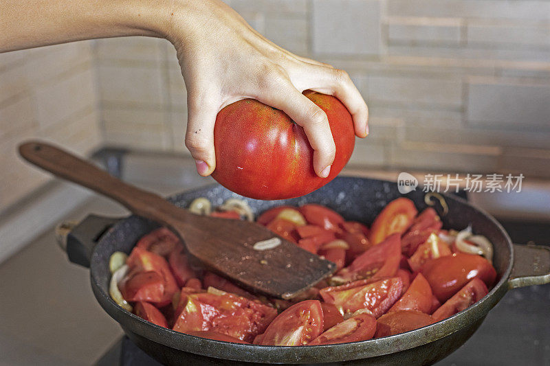 女孩用手在煎锅上拿着一个粉红色的西红柿。flatlay