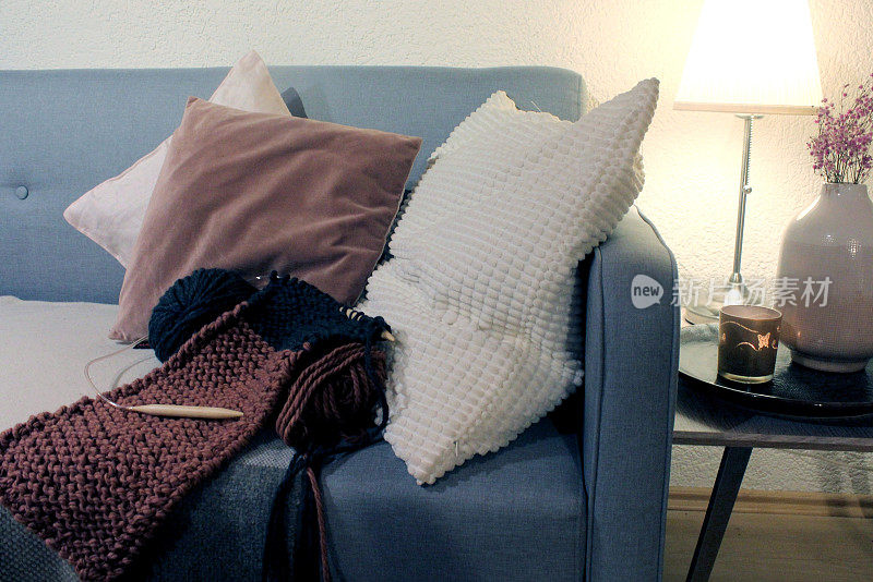 手工艺品:在客厅舒适的沙发上织围巾，羊毛，靠垫，边桌，花瓶，干花，灯，灯笼。