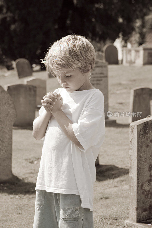 孩子在墓地为失去的亲人祈祷