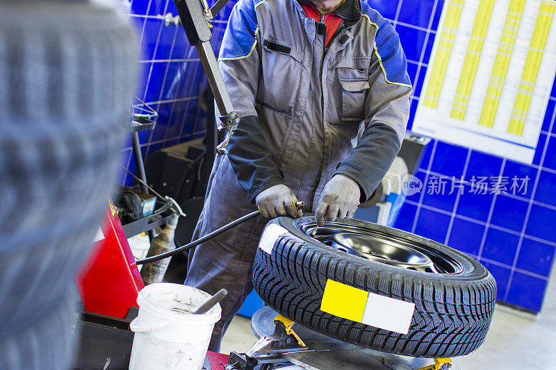在汽车修理厂…汽车修理工正在平衡冬季轮胎