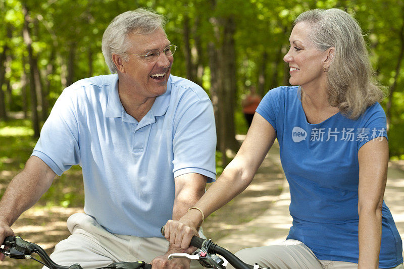 快乐的老夫妇一起在他们的自行车上笑