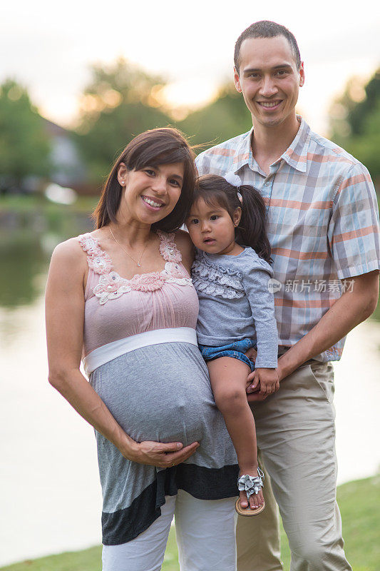 怀孕的夏威夷夫妇和年幼的女儿在户外公园