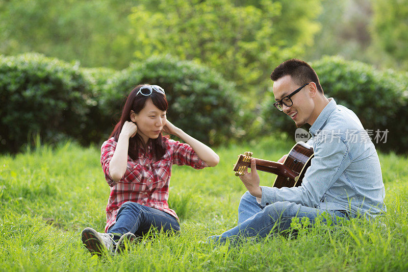 一对年轻夫妇在公园里弹吉他