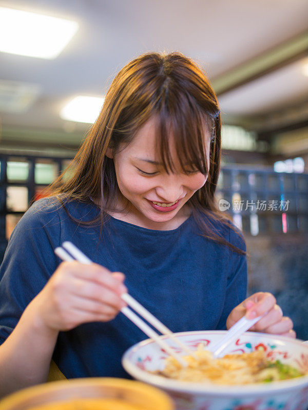 年轻女子在古老的日本餐馆吃拉面