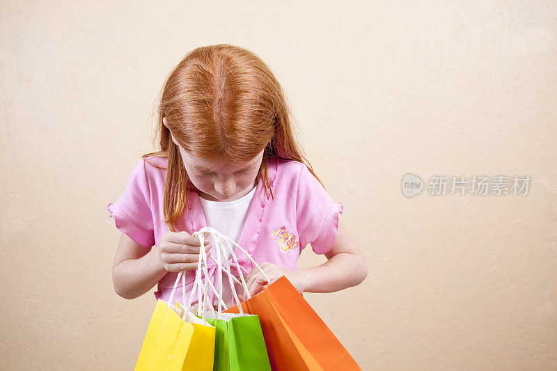 红头发的女孩拿着购物袋。