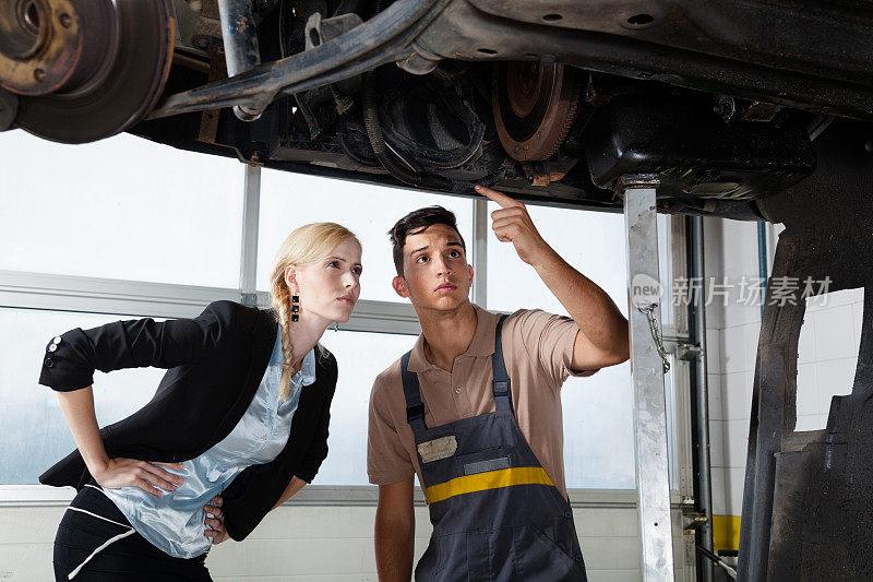 汽车修理工向客户展示有问题的管道