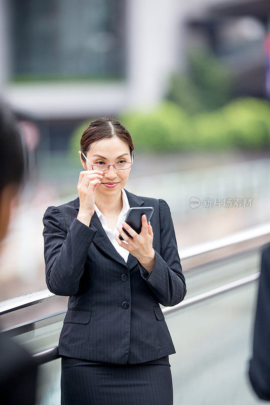 美丽的亚洲女商人在户外发短信