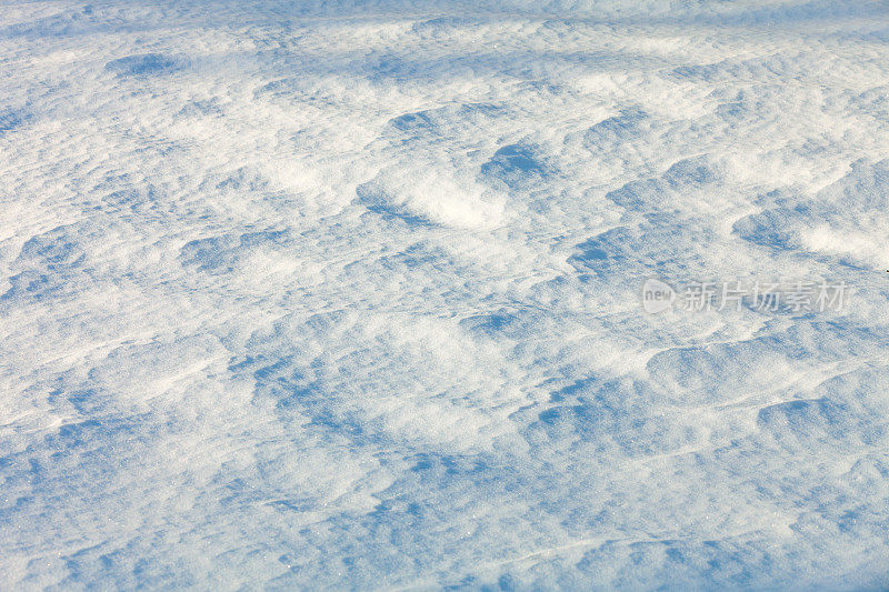 清晨阳光下的积雪覆盖地面，有漂移的图案