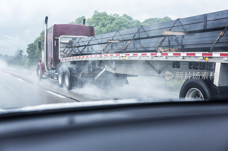 下着雨的高速公路上疾驶的钢梁平板拖车