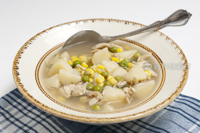 用勺子舀鸡汤的照片