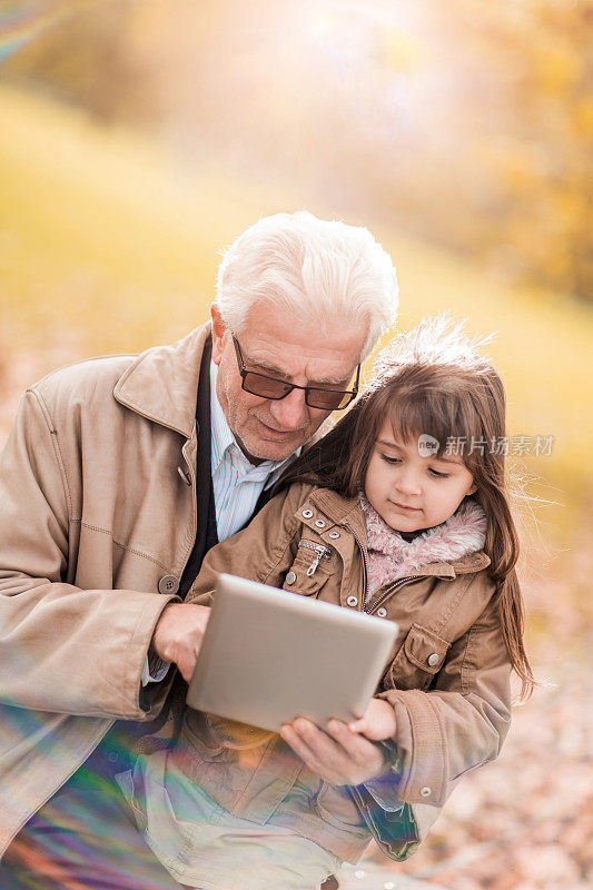 爷爷和孙女在公园里用触控板。