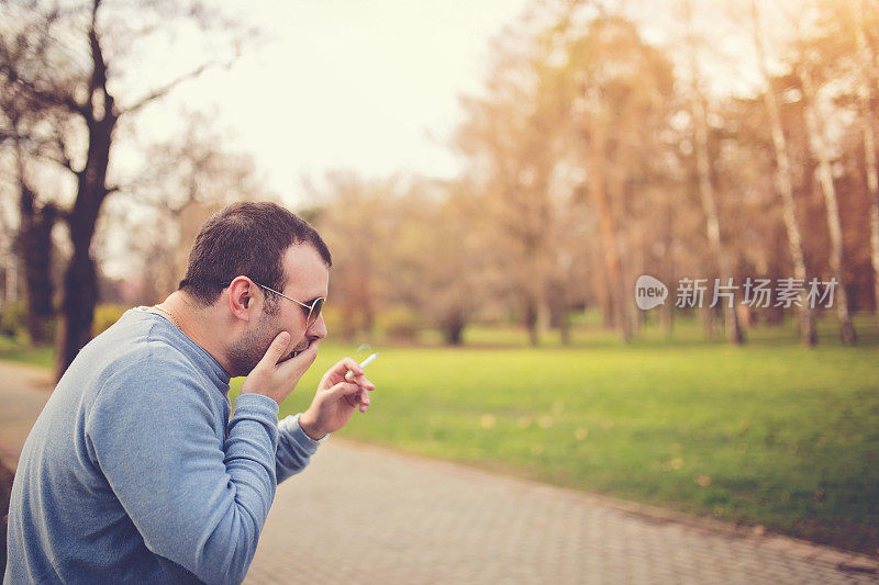 一个男人一边抽烟一边咳嗽