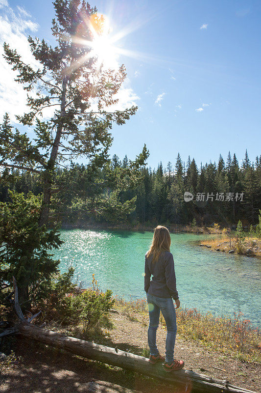 一个年轻女子在湖边徒步旅行，看风景