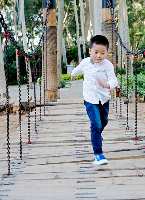 亚洲男孩跑过木桥