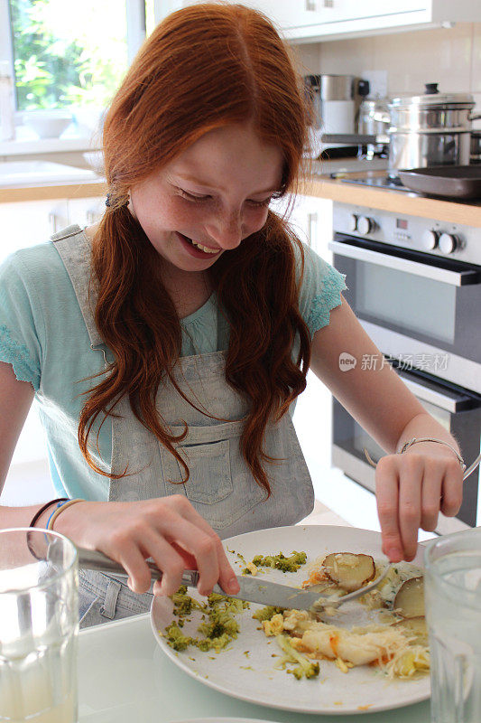 一个女孩晚餐在厨房的桌子上吃鱼派