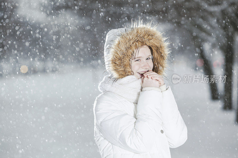 雪下穿着白色夹克的漂亮少女