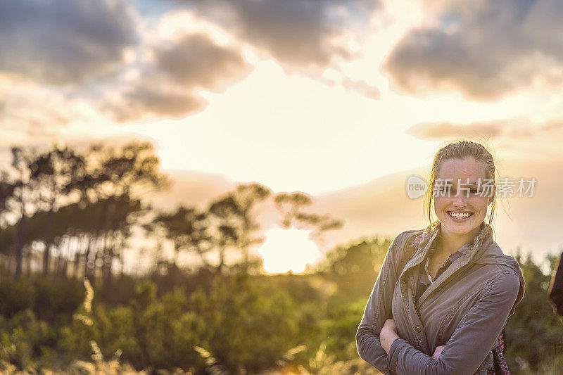 日落时分，在山上微笑的女性徒步旅行者