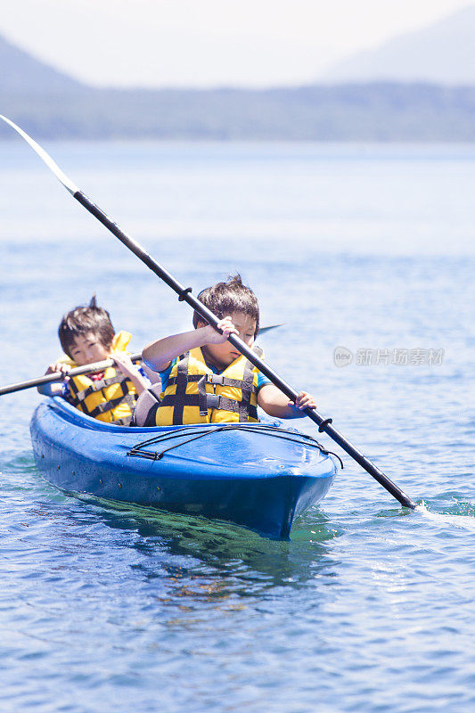 男孩们在双人皮划艇上划桨