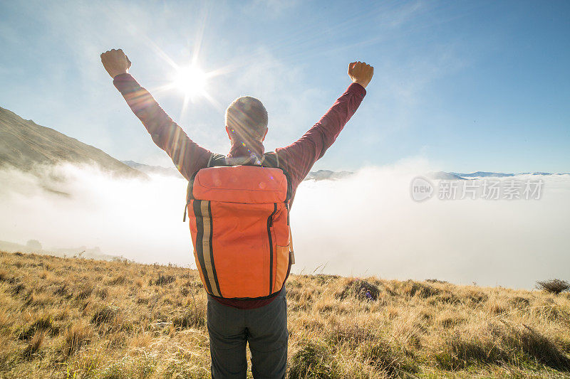 登山者在山顶上张开双臂庆祝成就