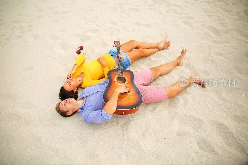 一对幸福的年轻夫妇躺在沙滩上