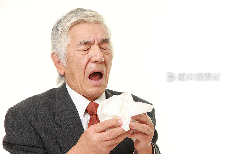 有过敏症状的日本资深商人对着纸巾打喷嚏