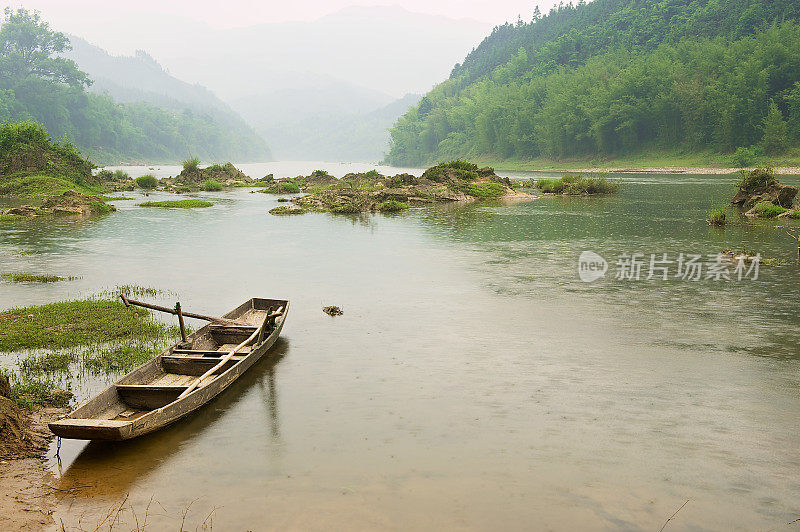 在雨天，中国广西城阳，一艘传统的木船停泊在河岸上。