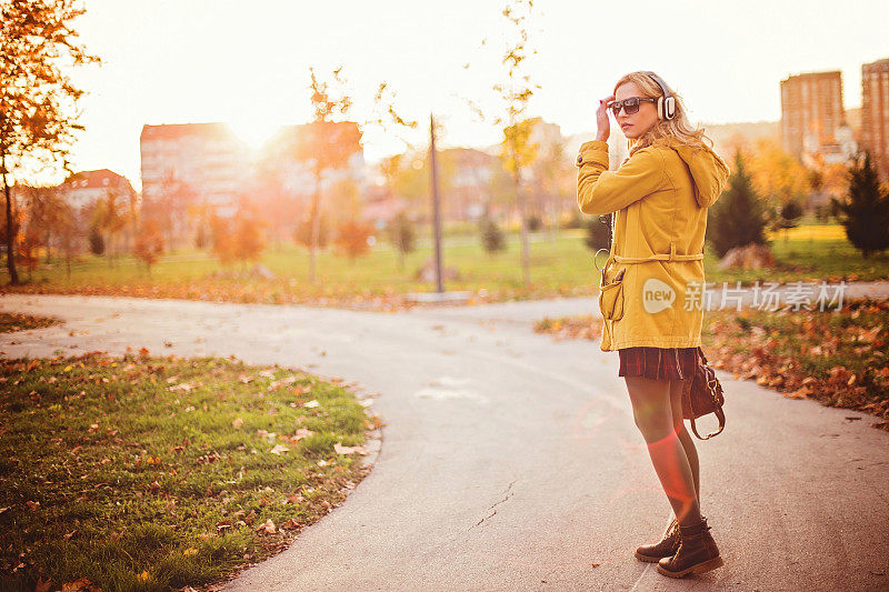 美丽的街头风情女子享受阳光明媚的秋日